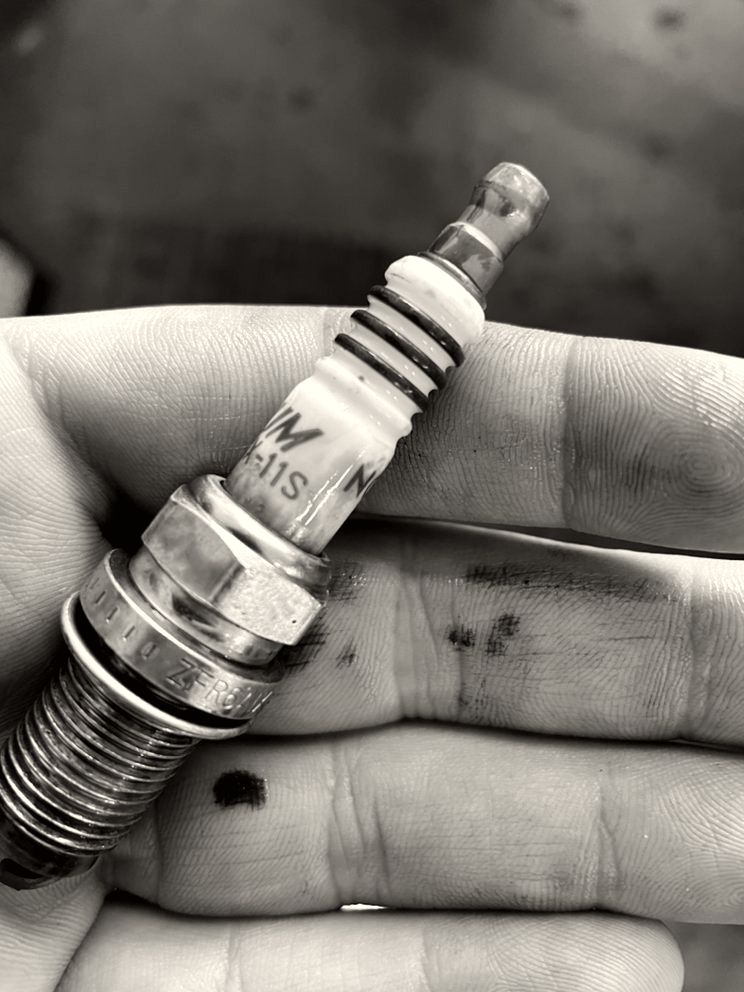 A worn spark plug held up in a mechanic's hand at Campbell All Car